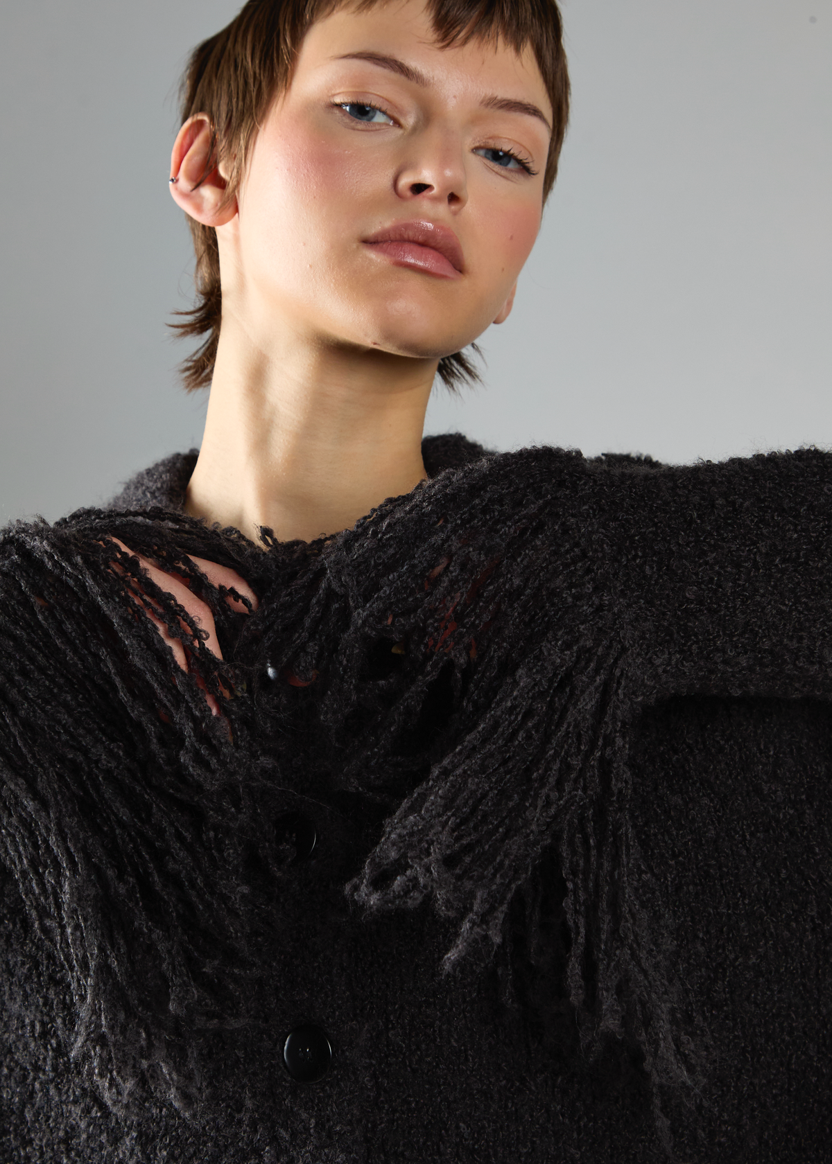 Person wearing a black textured cardigan with a neutral background