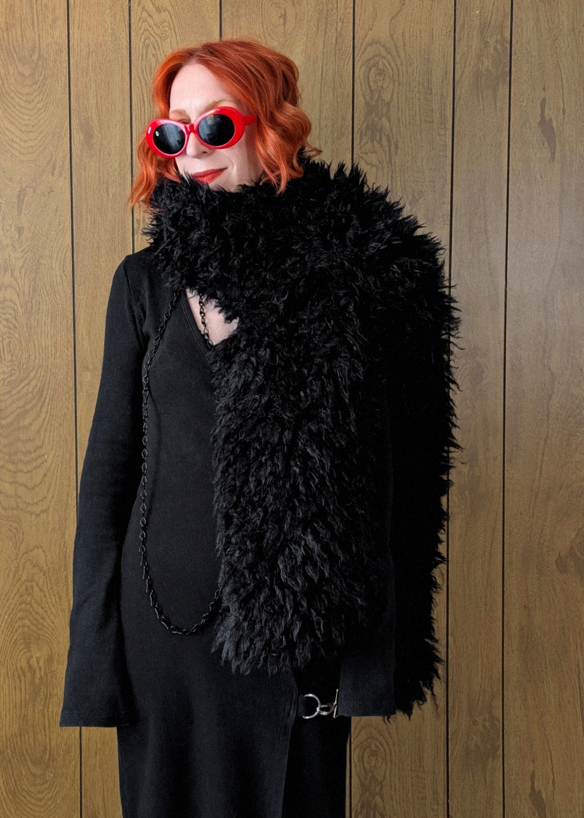 Woman with red hair wearing an oversized extra long black faux fur scarf styled with a ribbed black maxi dress