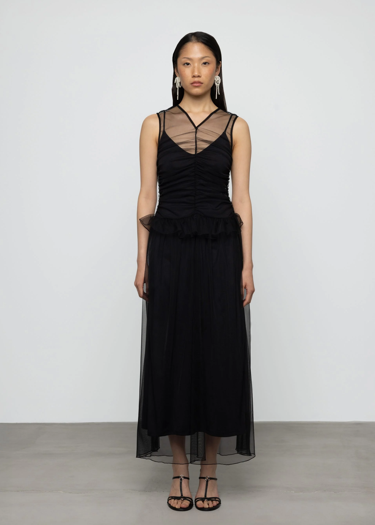Woman wearing a black dress with sheer tulle panels on a white background