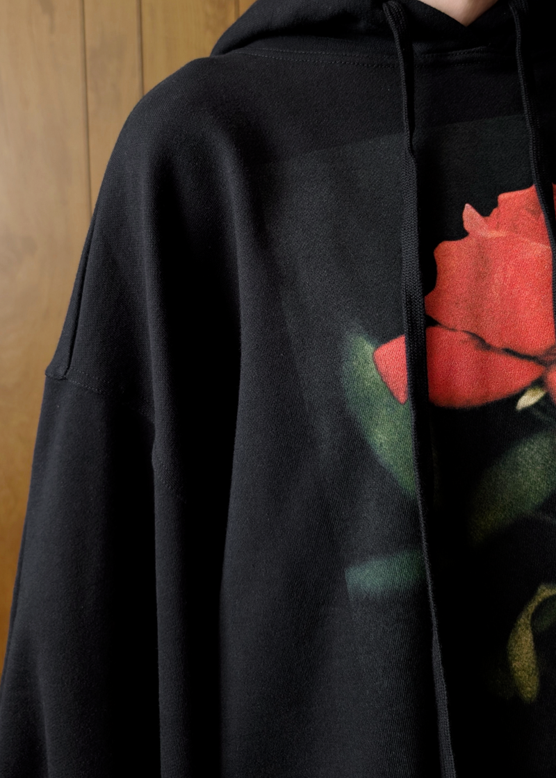 Black hoodie with a red rose design on a wooden background