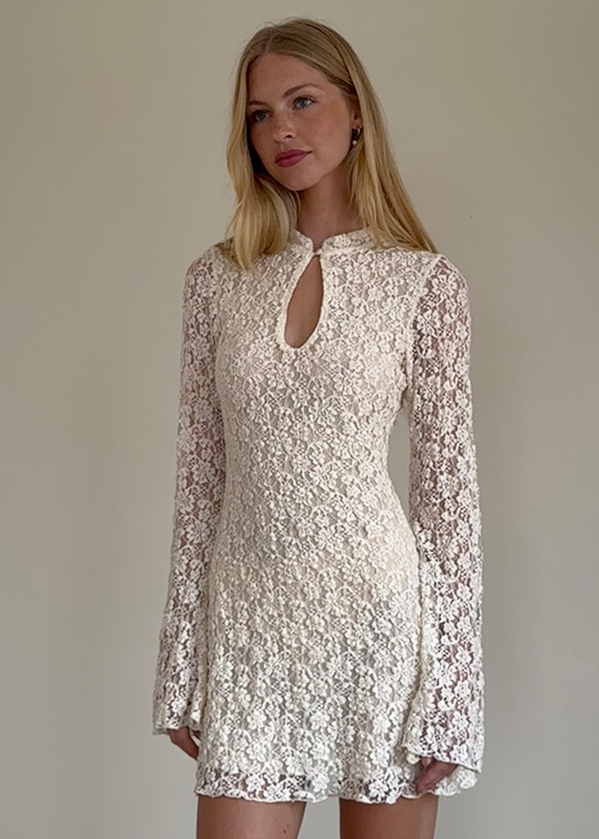 60s-inspired wedding dress! Ivory Floral Lace Bell Sleeve Mini Dress with high neckline and keyhole cutout at front. Lined through the body, sheer through sleeves. By Motel Rocks. 