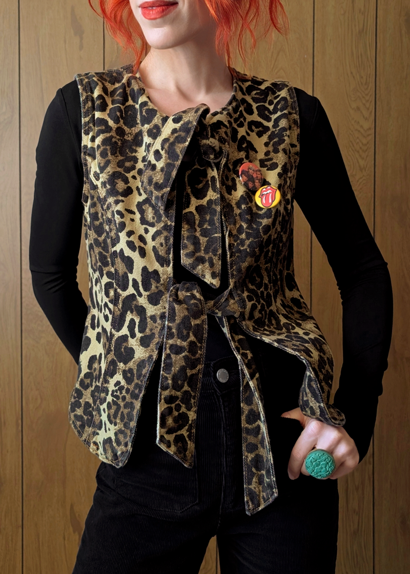 Person wearing a leopard print vest with a wooden background