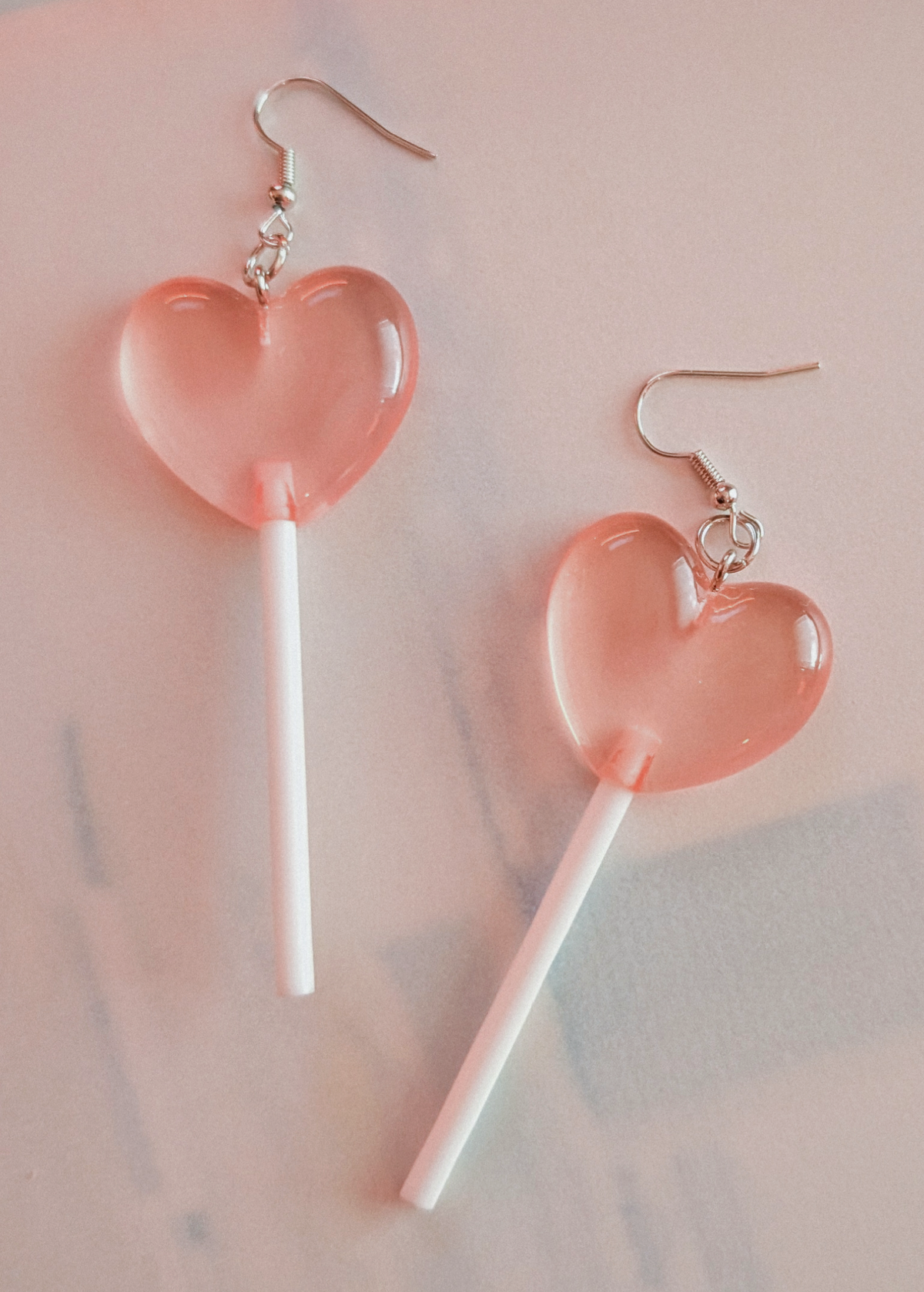 Heart-shaped lollipop earrings on a light pink background
