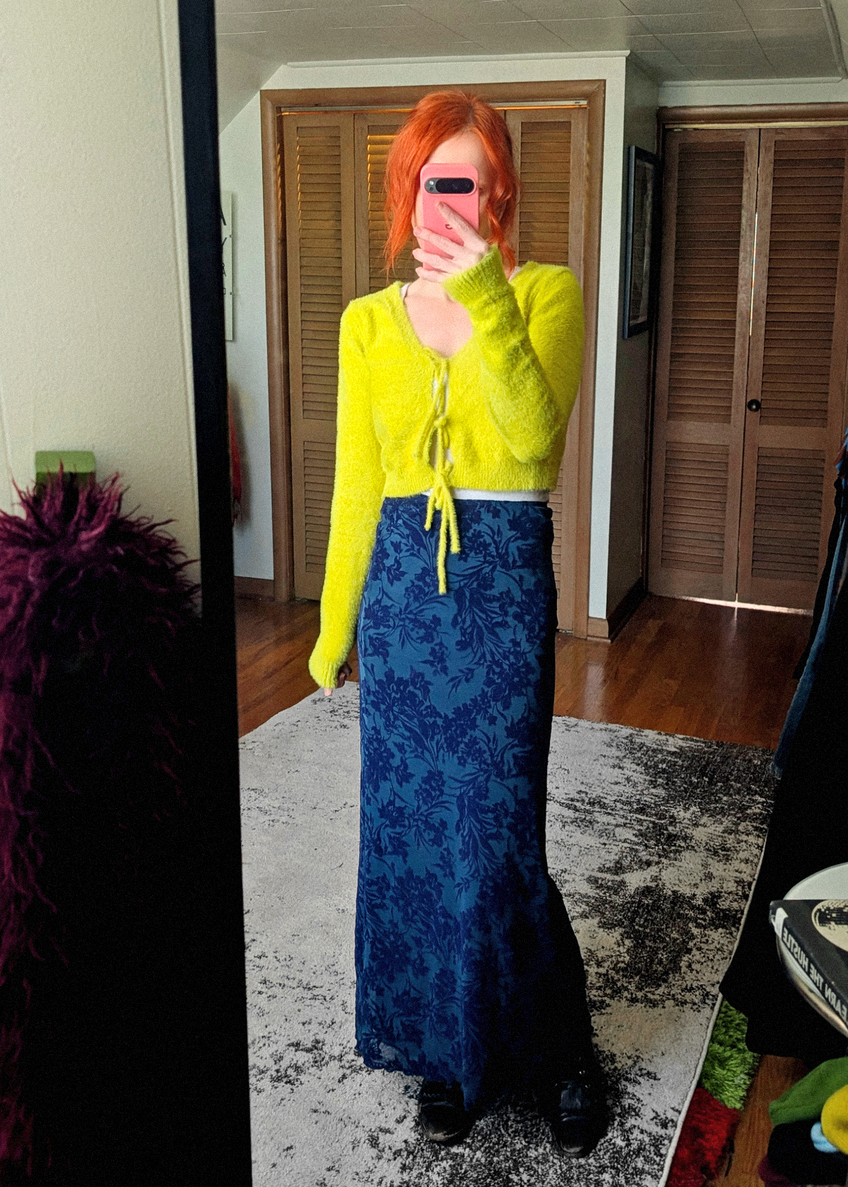 Person wearing a lime green crop sweater and blue flocked mesh floral skirt taking a mirror selfie.