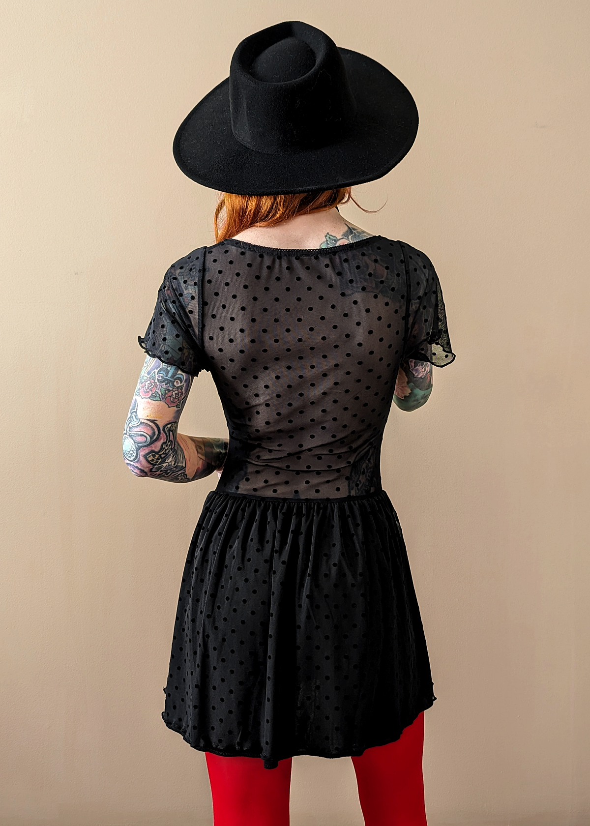 90s inspired black mesh mini dress with black velvet flocked dots allover. Features flutter short sleeves, v-neckline with red satin rosette, sheer waist, and floaty skirt. By Motel Rocks