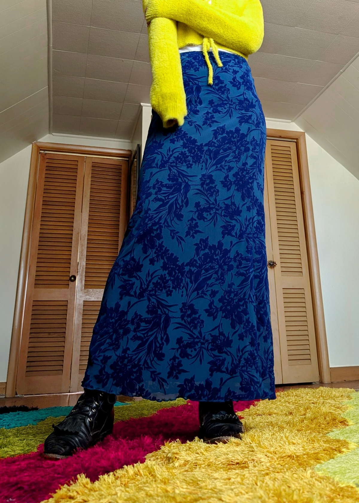 Person wearing a lime crop sweater and royal navy flocked mesh floral skirt standing on a colorful rug.