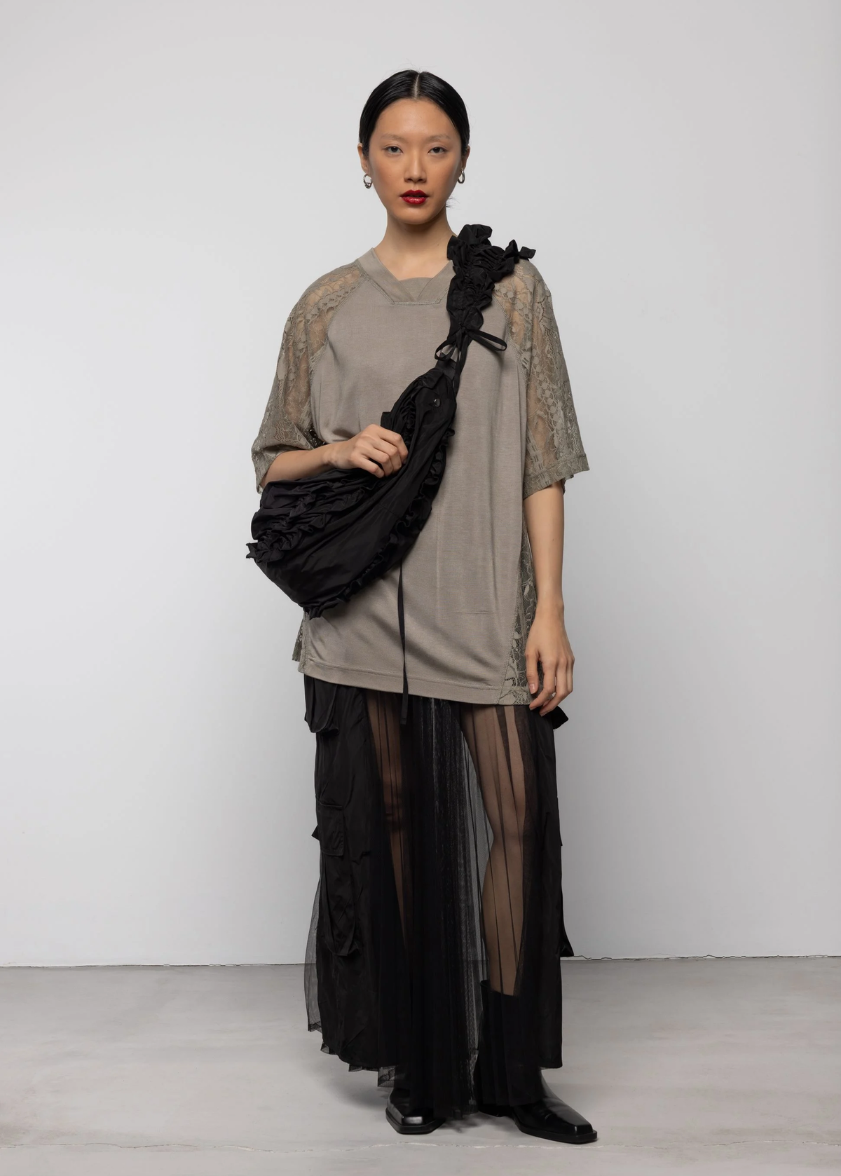 Woman wearing a beige top and black sheer mesh cargo skirt against a white background