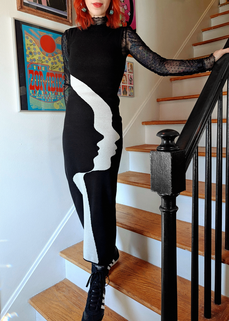 Person wearing a black and white dress with face design on a staircase.
