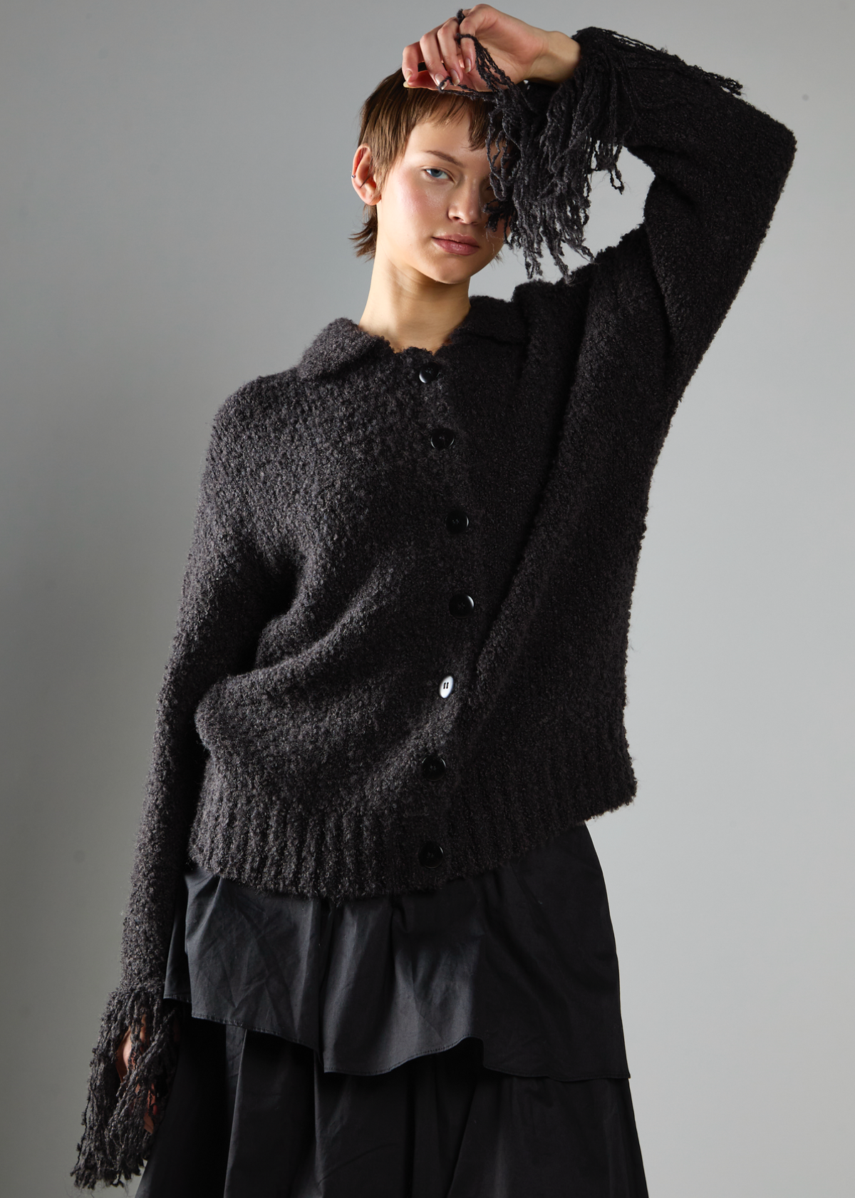 Person wearing a black textured sweater against a gray background