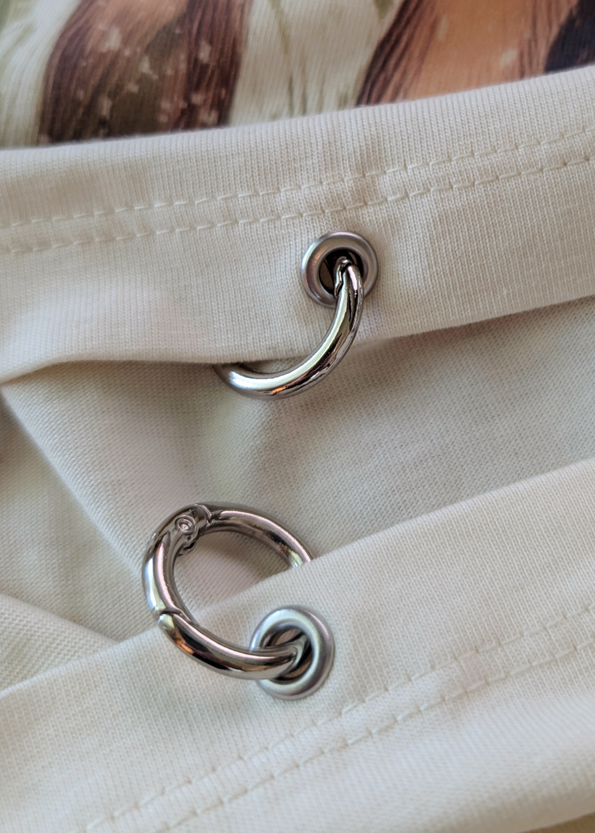 Close-up of the ivory t-shirt with metal rings at hem