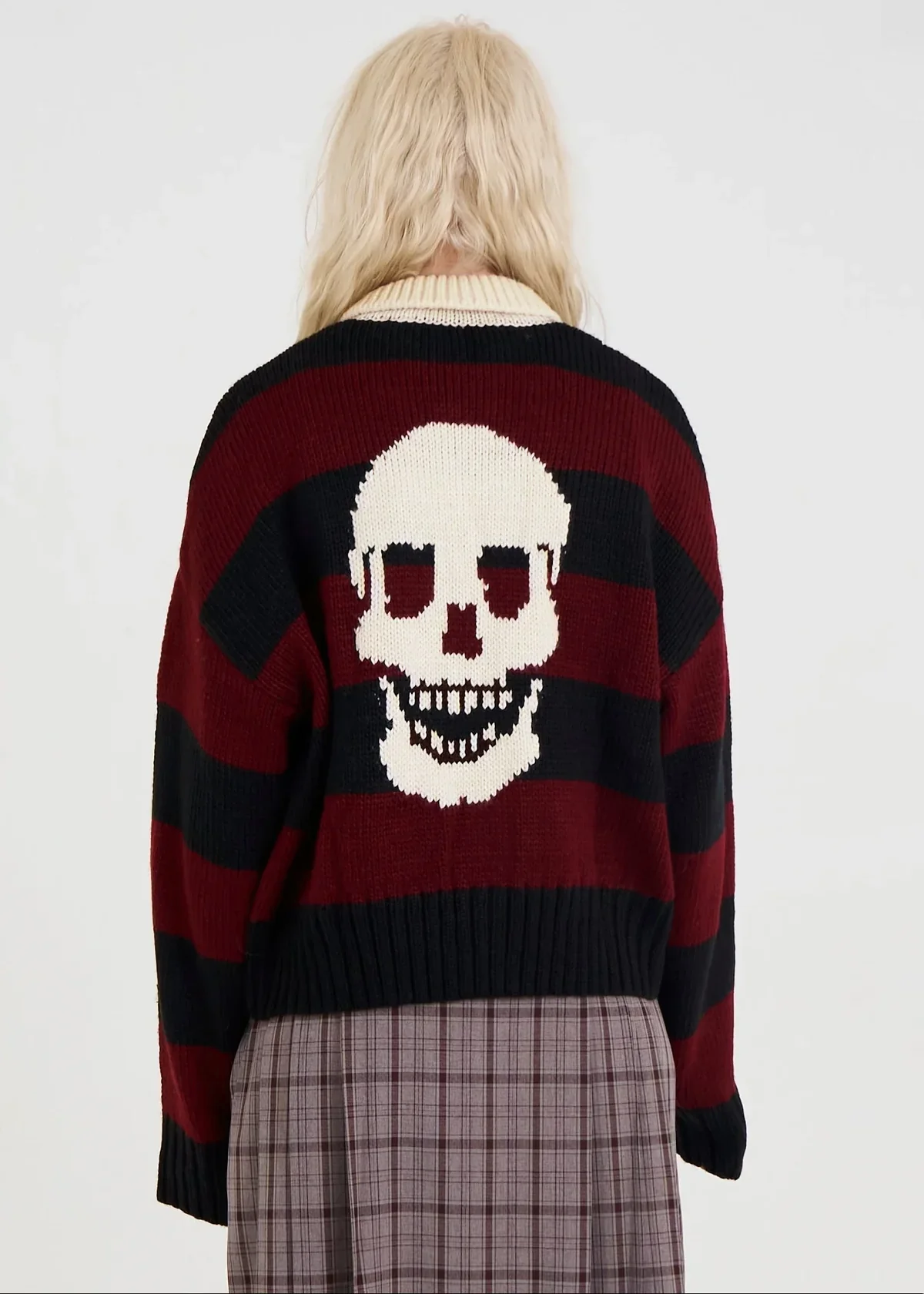 Person wearing a sweater with a skull design on a plain background