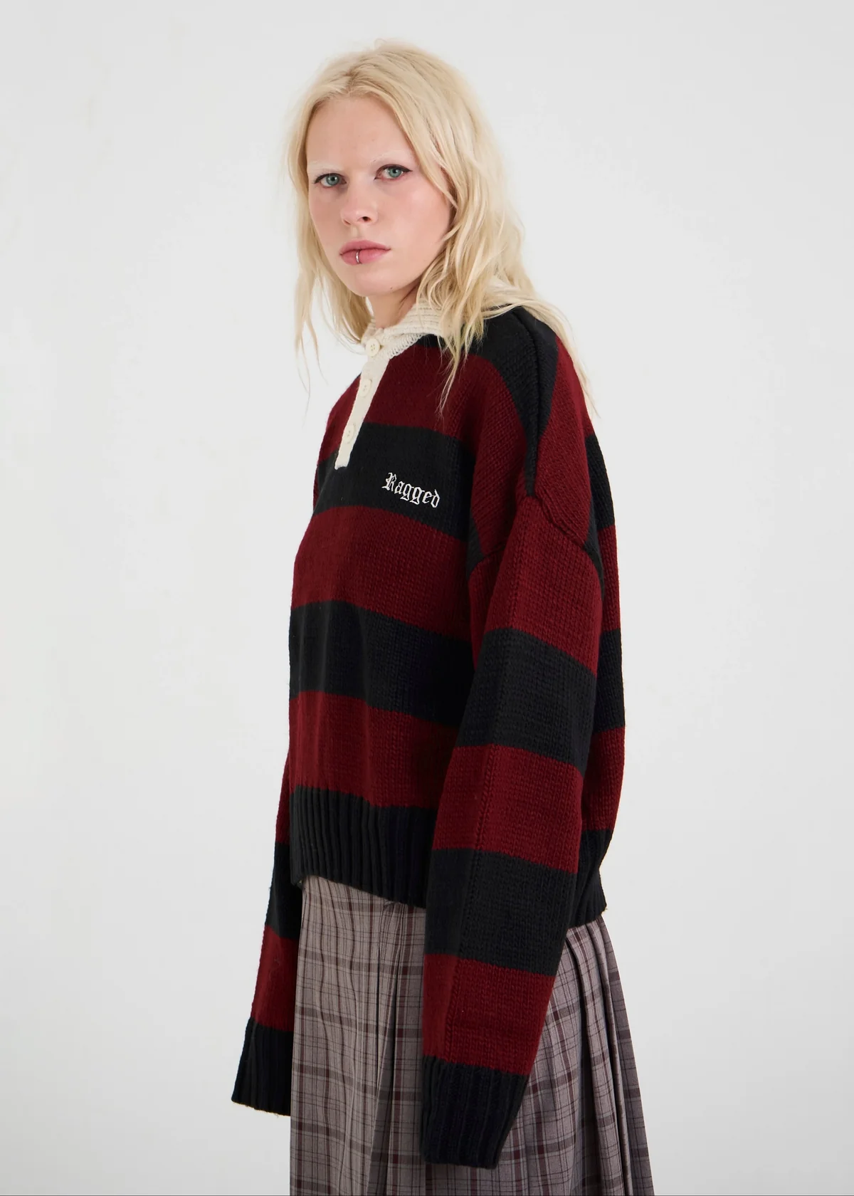 Person wearing a red and black striped sweater with a brand logo on a white background