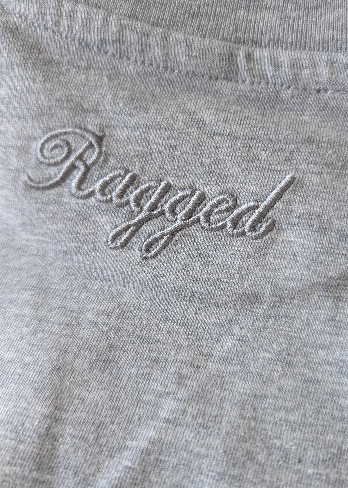 Close-up of a gray fabric with 'Ragged' embroidered on it