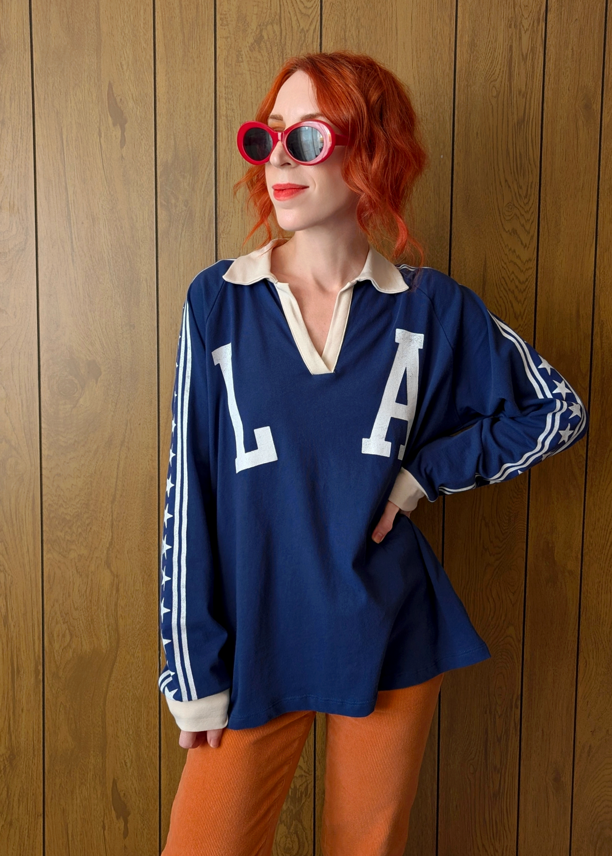 Person wearing a blue 'LA' jersey with orange pants against a wooden background
