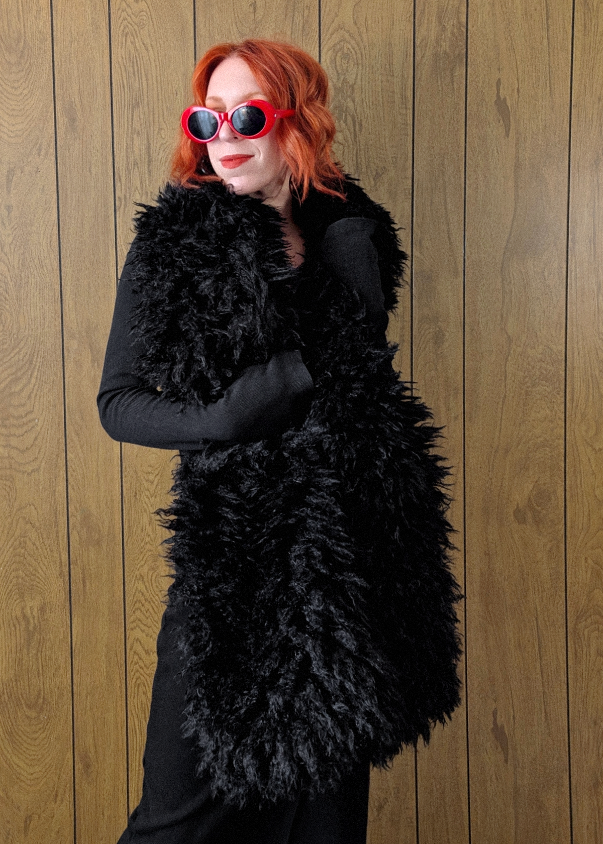Woman with red hair wearing an oversized extra long black faux fur scarf styled with a ribbed black maxi dress