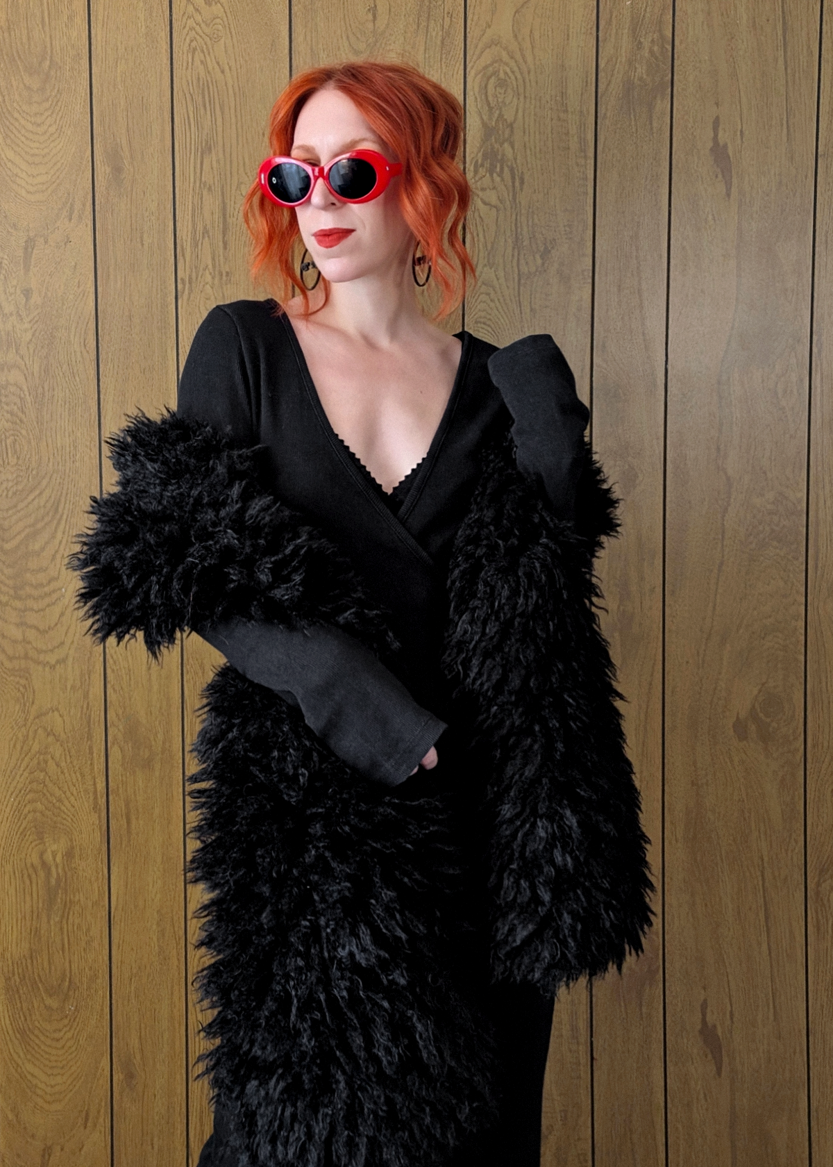 Woman with red hair wearing an oversized extra long black faux fur scarf styled with a ribbed black maxi dress