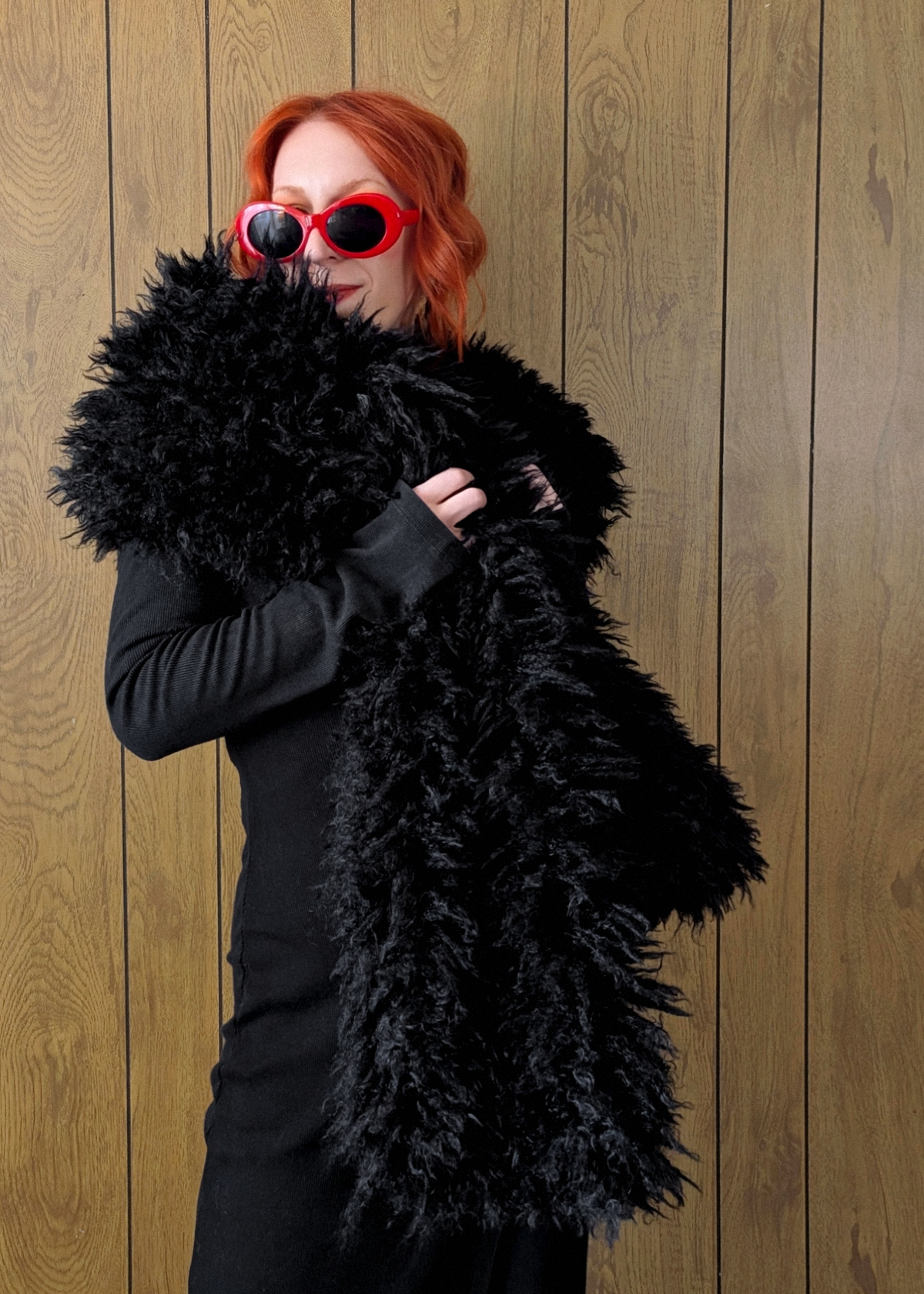 Woman with red hair wearing an oversized extra long black faux fur scarf styled with a ribbed black maxi dress