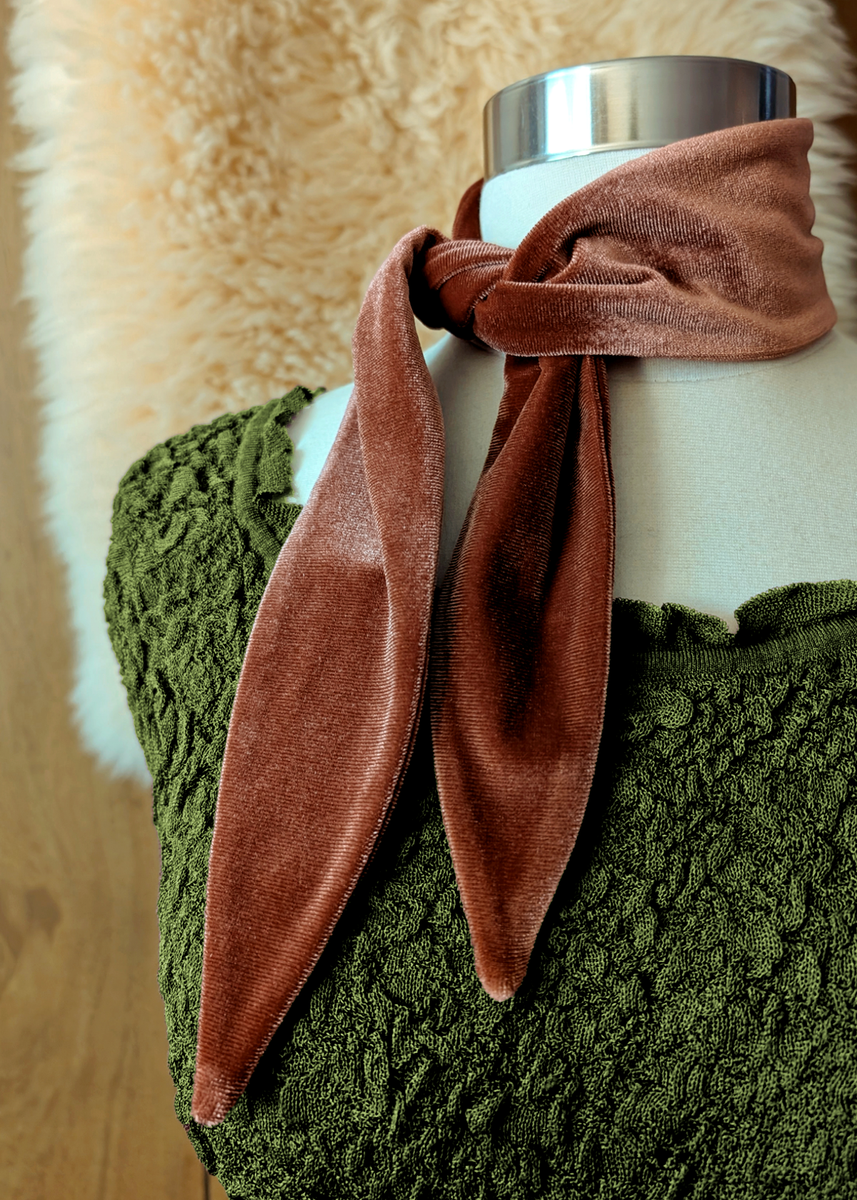 Brown velvet scarf tied around a white mannequin's neck with a green texture dress