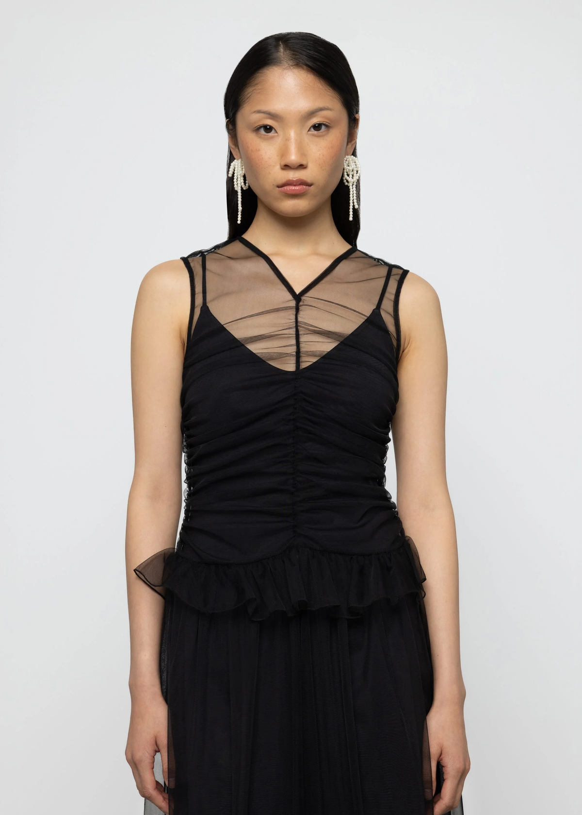 Woman wearing a black dress with sheer panels on a white background