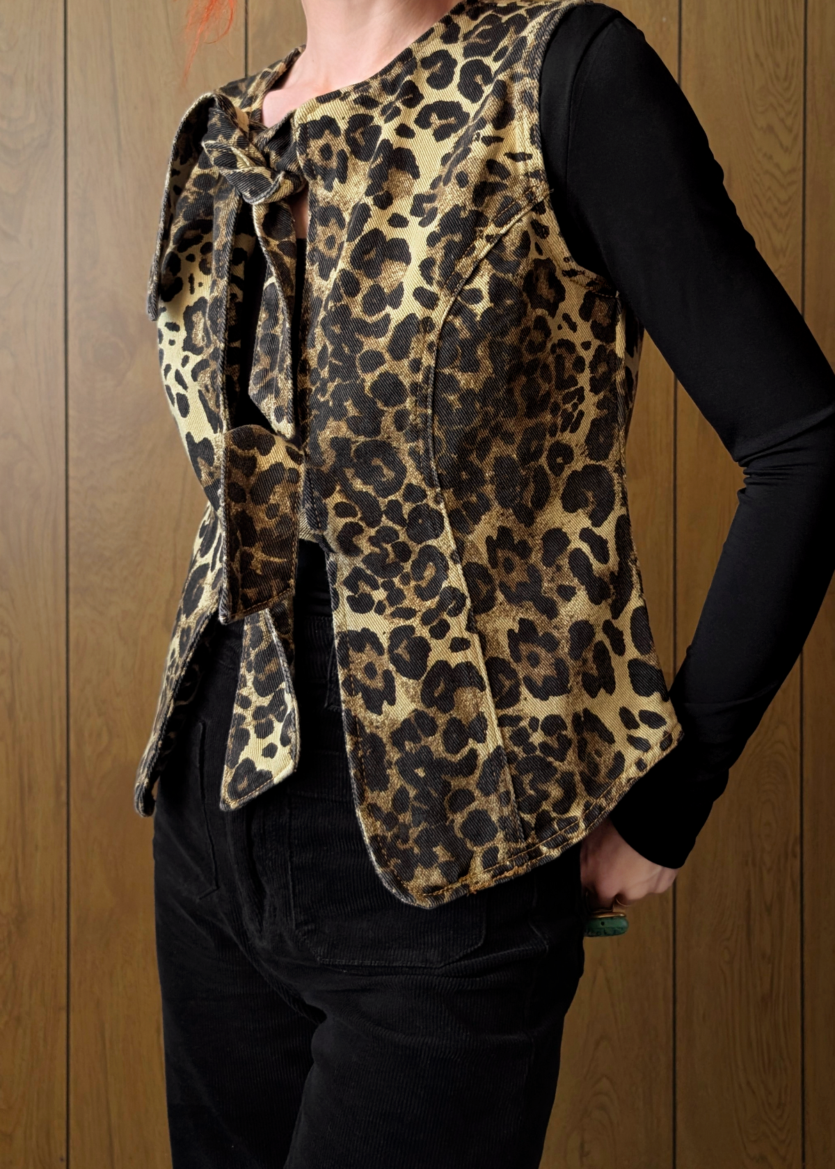Leopard print vest worn by a person against a wooden background