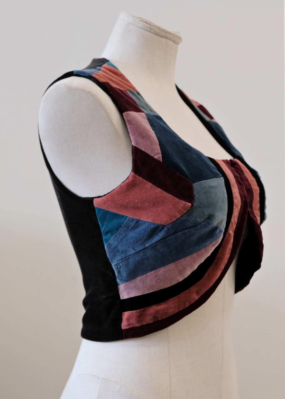 vintage 1970s patchwork velvet bolero vest in mauve, burgundy, dusty rose and dusty blues, and black with hook and eye closures at front and solid black velvet back.