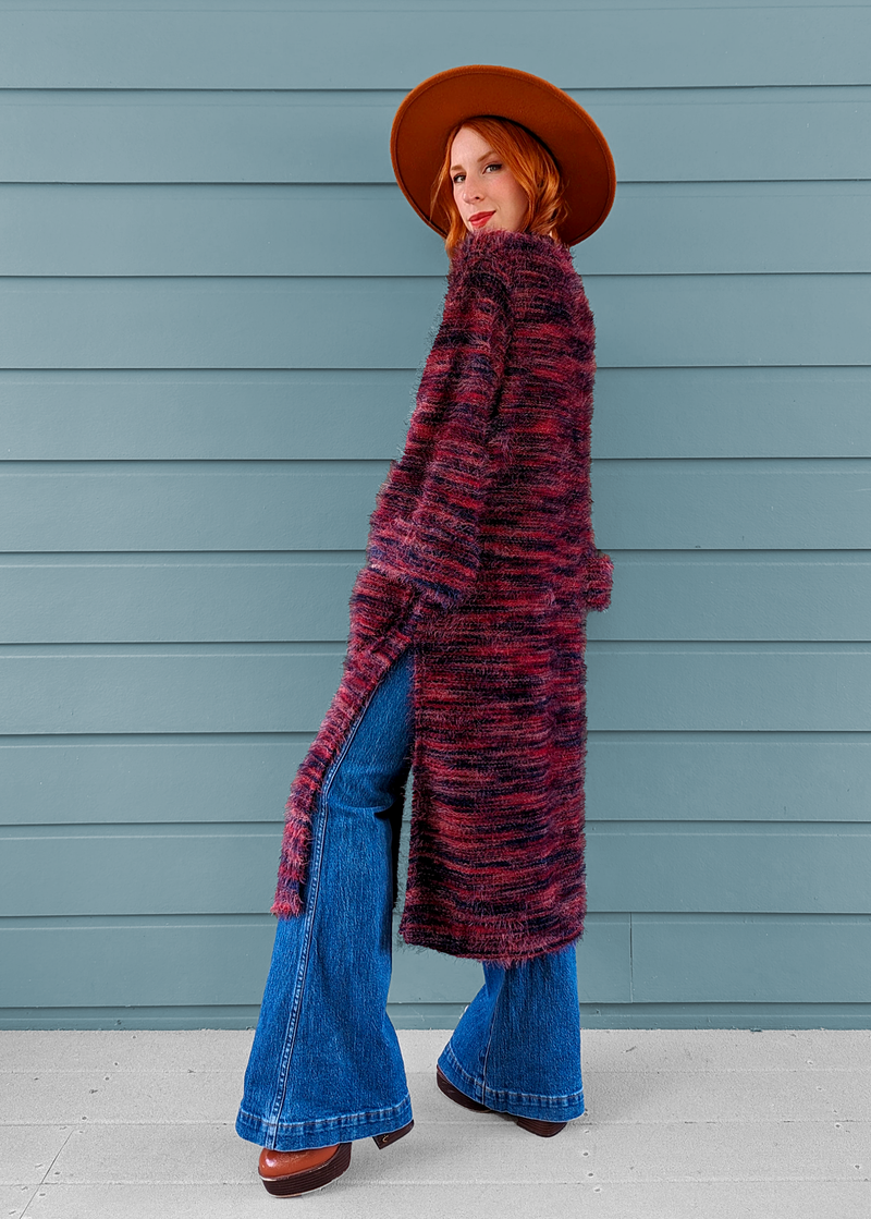 70s inspired fuzzy eyelash knit cardigan duster with a midi-maxi length. Features an open front, wide bell cuffed sleeves, and a pink, red, and purple spacedye design
