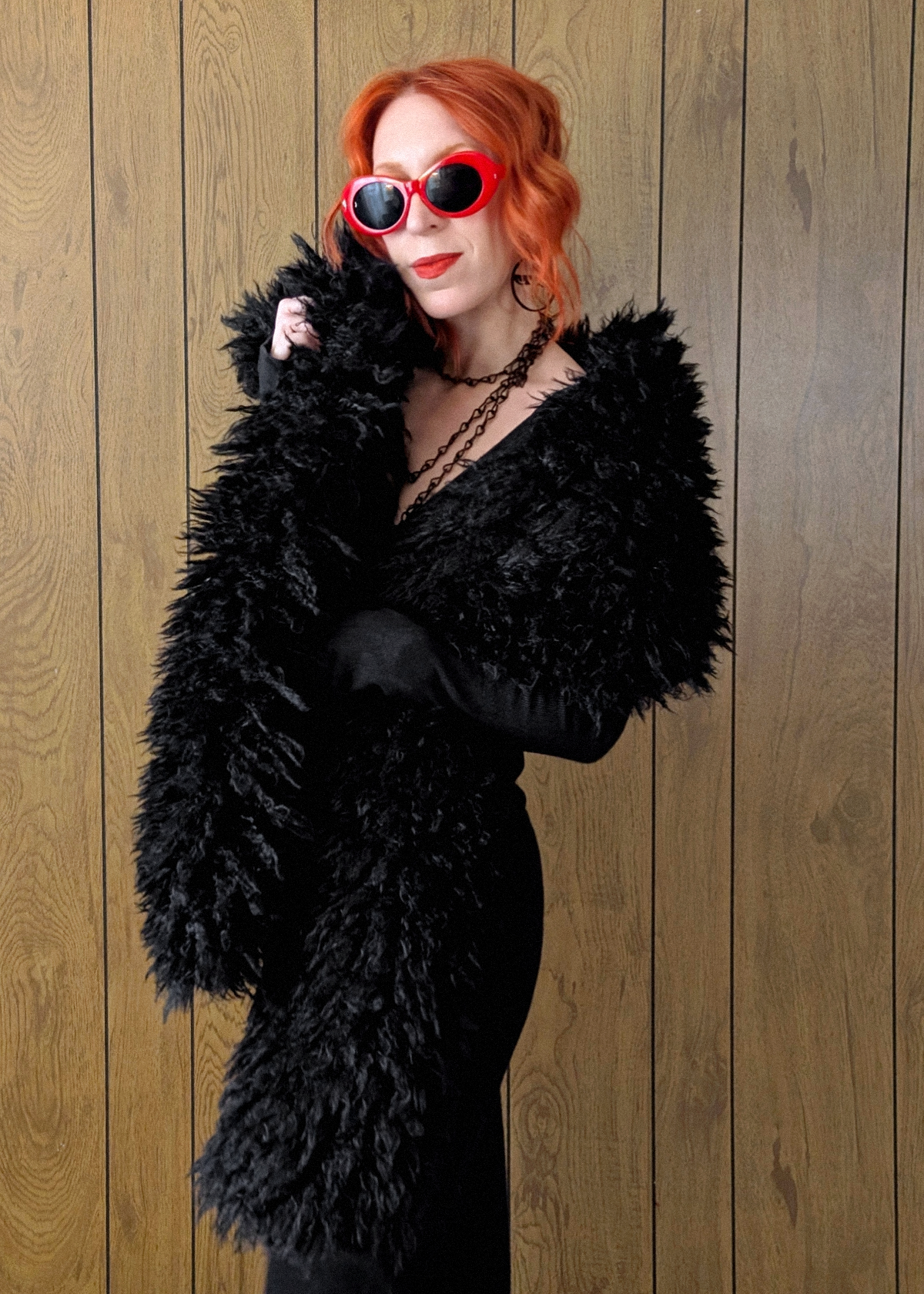 Woman with red hair wearing an oversized extra long black faux fur scarf styled with a ribbed black maxi dress
