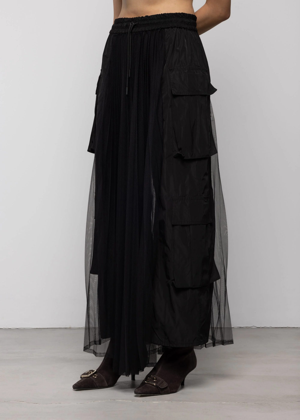 Black sheer pleated skirt with black cargo pockets on a plain background