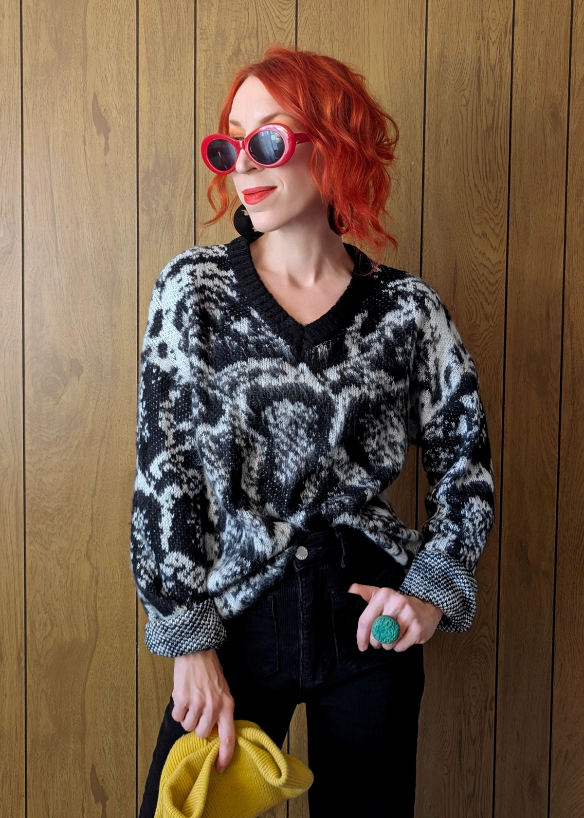 Woman wearing a patterned sweater and sunglasses against a wooden background