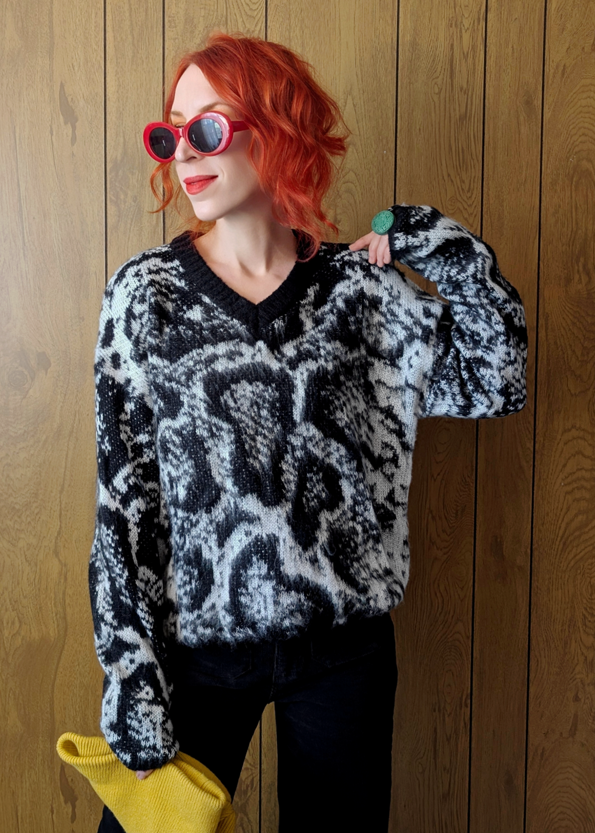 Person wearing a black and white patterned sweater against a wooden background