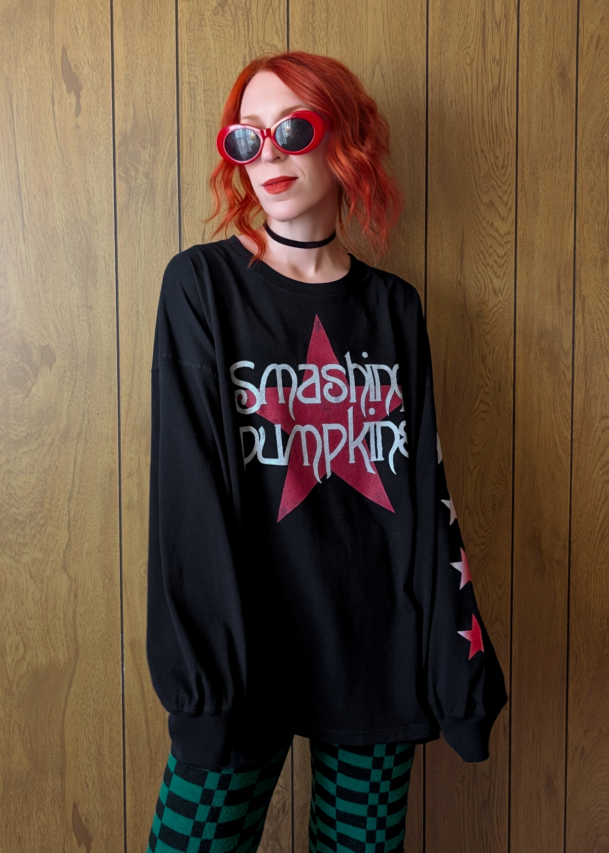 Person wearing an oversized black long sleeve t-shirt with Smashing Pumpkins star design at front and stars down one sleeve