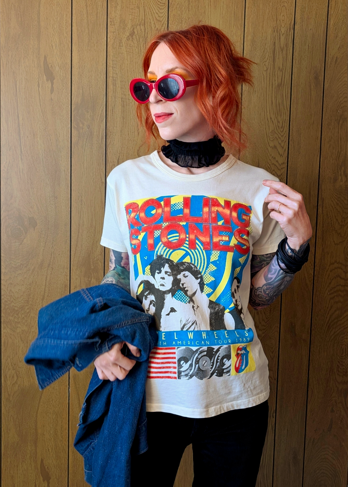 Person wearing a Rolling Stones t-shirt against a wooden panel background