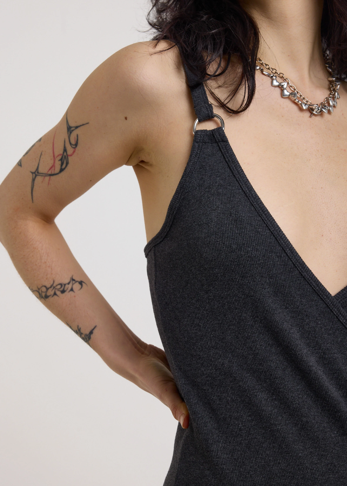 Woman wearing a charcoal grey ribbed tank midi dress with buckles against a white background