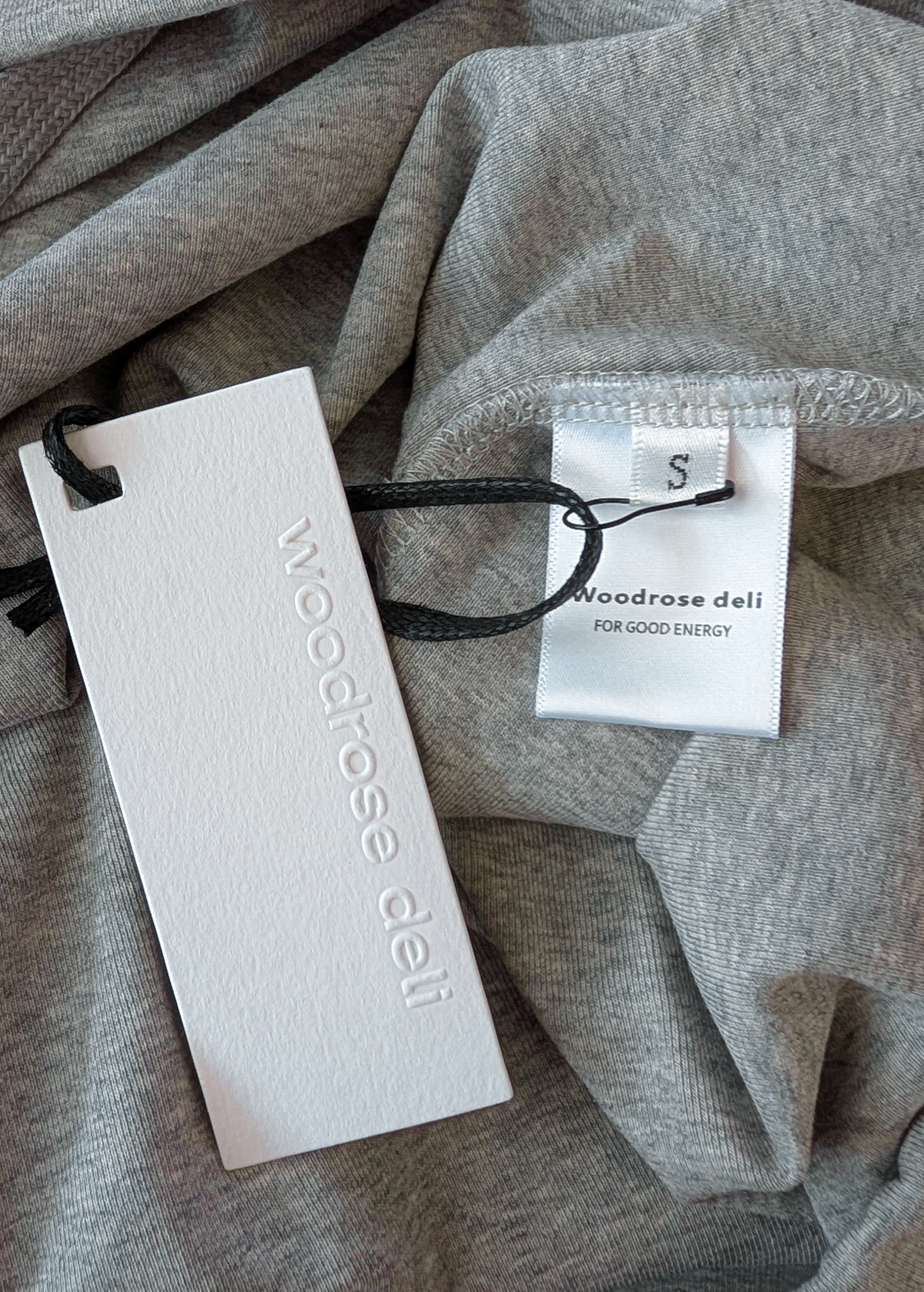 Close-up of Woodrose Deli tags on a grey jersey shirt