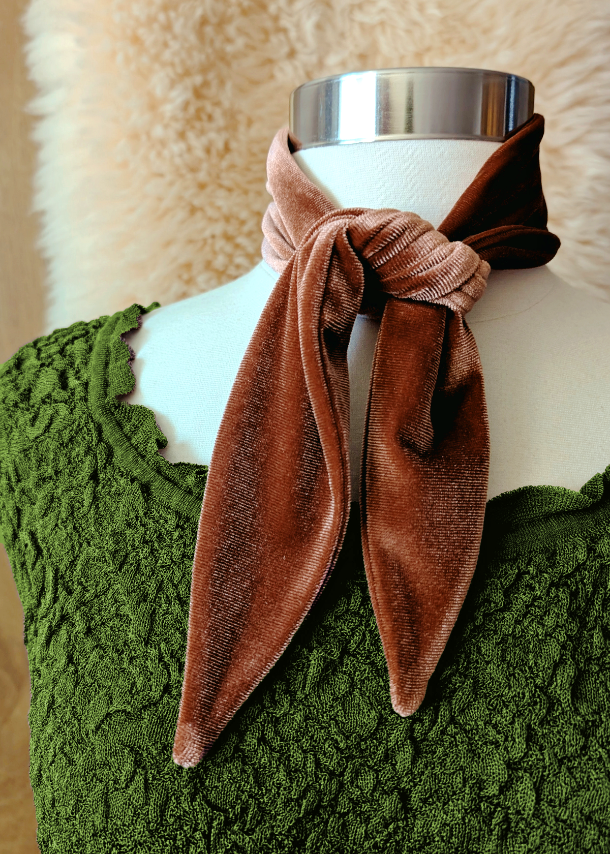 Brown velvet scarf knotted over a white mannequin's neck with a green texture dress
