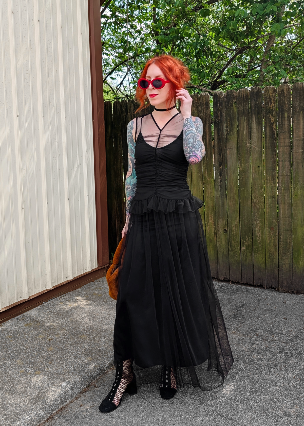 Person wearing a black tulle dress, standing outdoors.