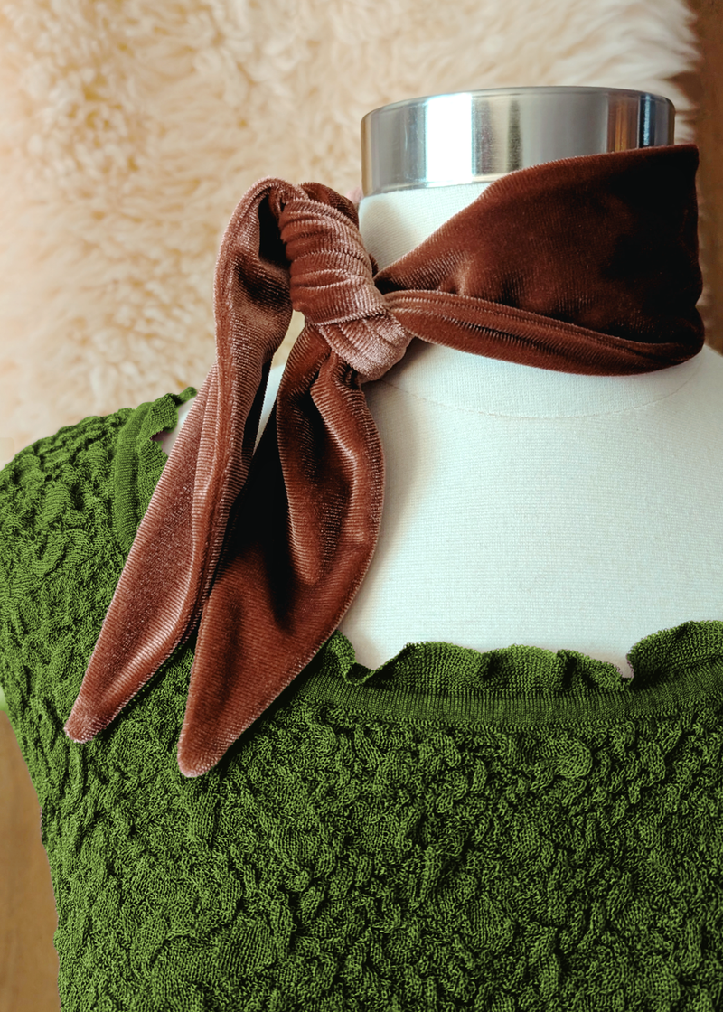 Brown velvet scarf knotted over a white mannequin's neck with a green texture dress