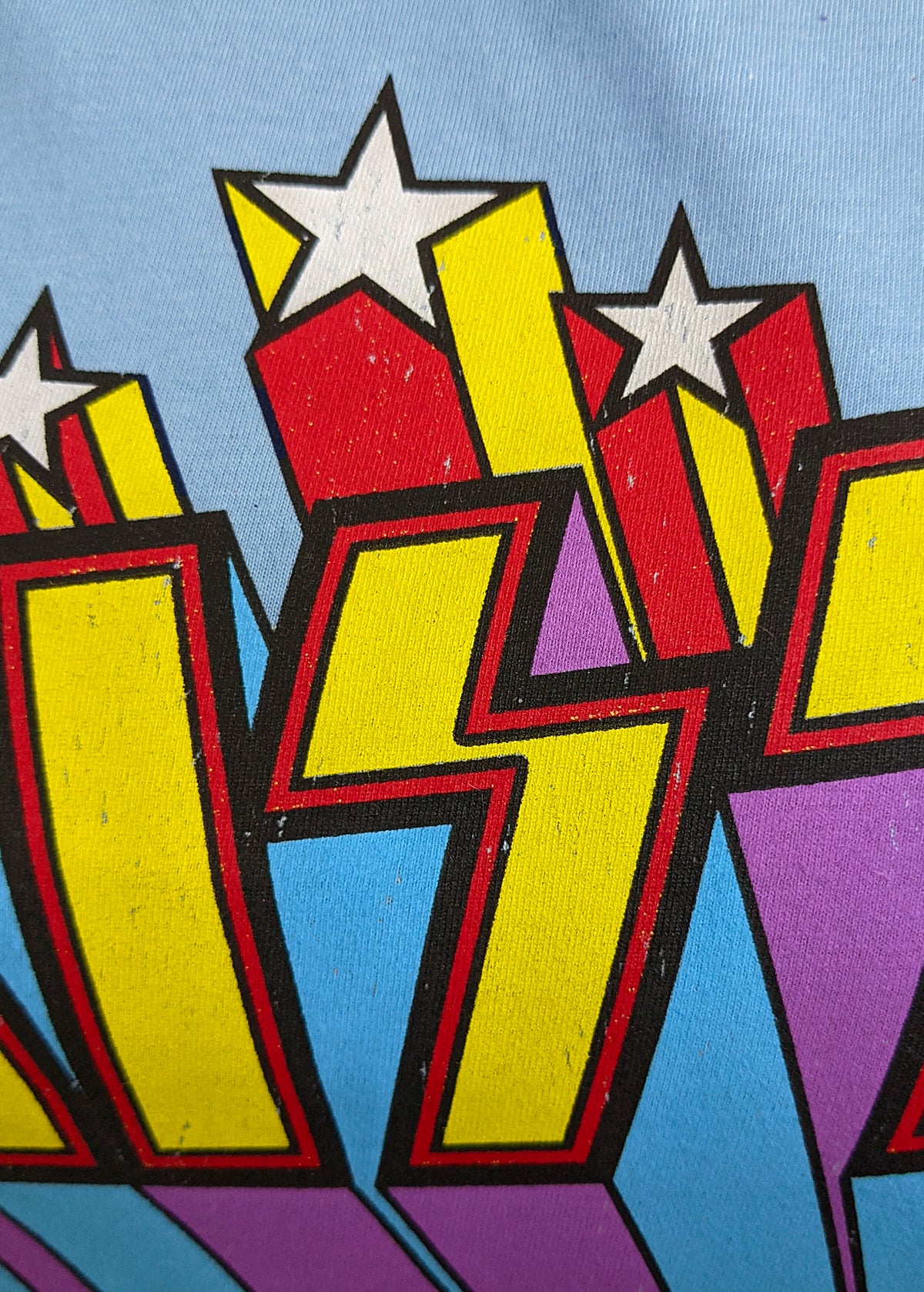 Retro Fitted sky blue KISS band tee with rainbow and stars design in yellow, purple, blue, and red. Officially licensed.
