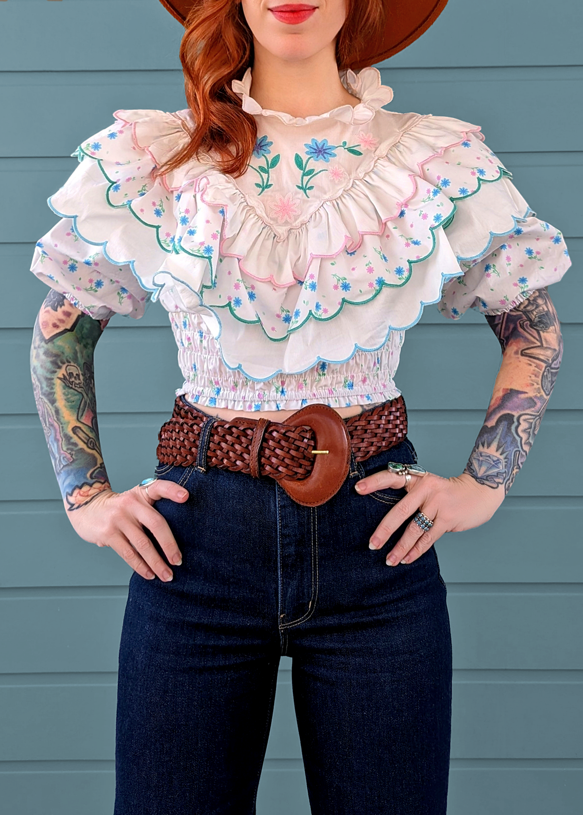 80s inspired prairie ruffle crop blouse with tiered ruffles, high neckline, embroidered floral details, puff sleeved, and smocked bottom. White cotton with blue and pink floral pattern. By Glamorous UK